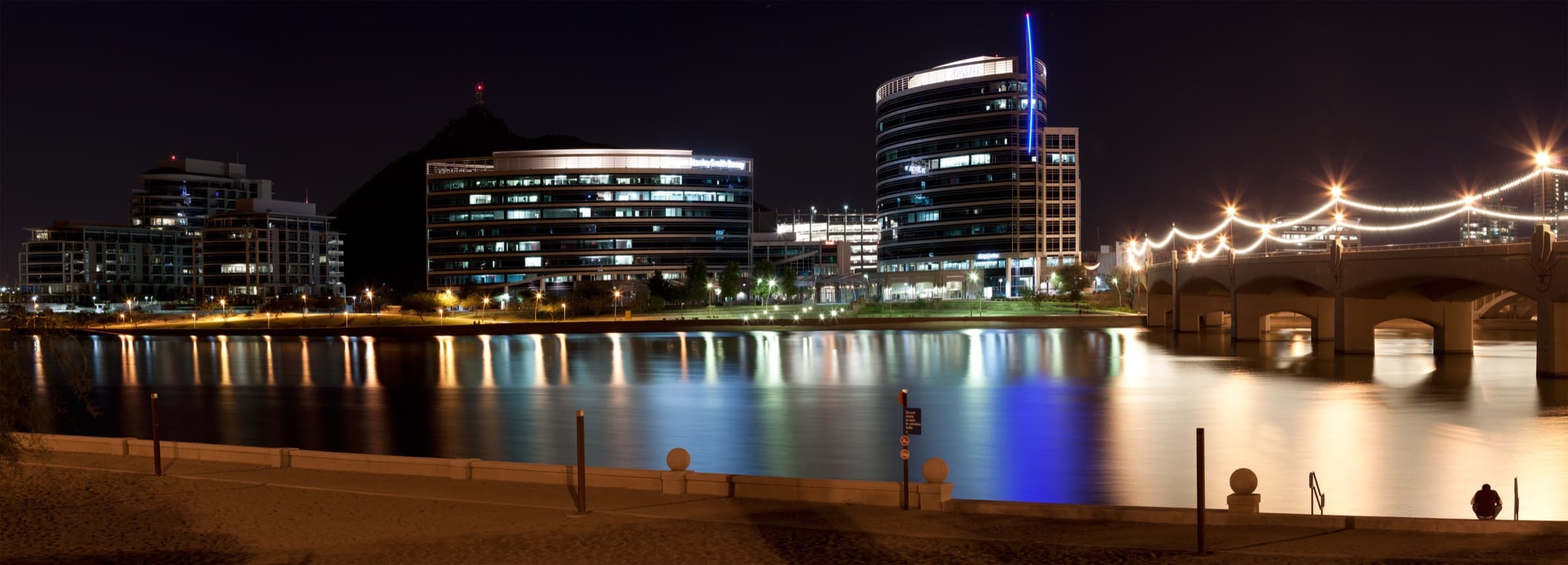 Tempe Town Lake at night with the Mill Avenue Bridge, downtown skyline, and 'A' Mountain in the background