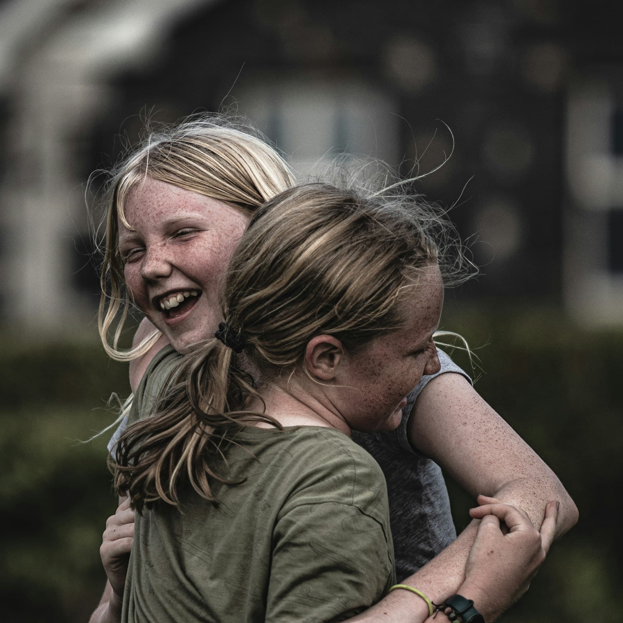 Two happy kids laughing and hugging outside a home